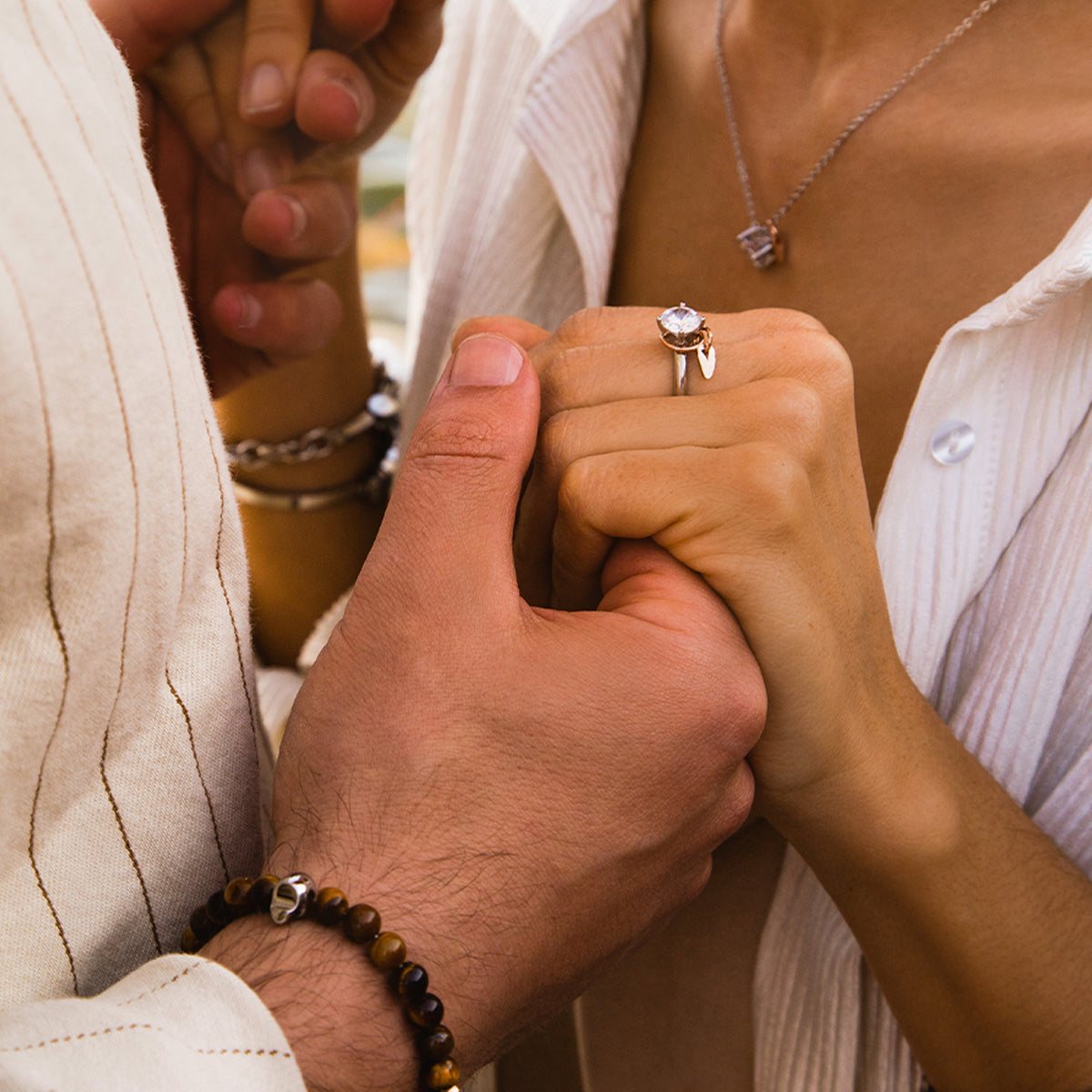 Close-up of couple holding hands, showcasing AN JEWELS JEWELRY Mod. AA.P255RBR ring and necklace.