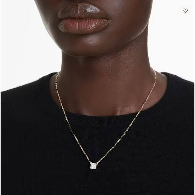 Close-up of a person wearing a delicate gold necklace with a square pendant on a black top