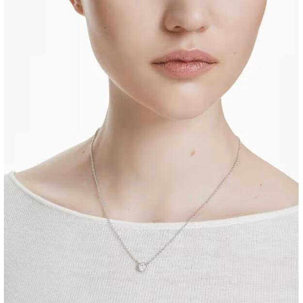 Elegant woman wearing Swarovski Mod. 5696039 Imber pendant necklace, round cut, rhodium plated, minimalist design.