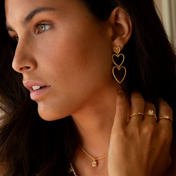 Model wearing 24KAE JEWELS JEWELRY Mod. 12472Y/52, featuring heart earrings, gold necklace, and rings.