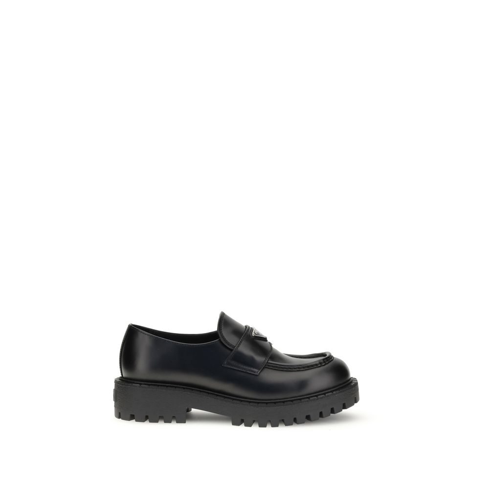 Prada Black Calf Leather Bos Taurus Slip-On Loafers with enameled triangle design and rubber sole on white background.