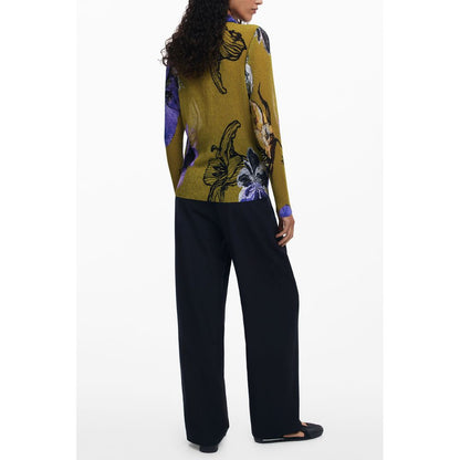Back view of model wearing vibrant floral long-sleeved sweater with black pants and flats
