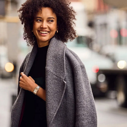 Stylish woman wearing a BULOVA WATCHES Mod. 98L328 on her wrist while walking in a cityscape, showcasing fashion and elegance.