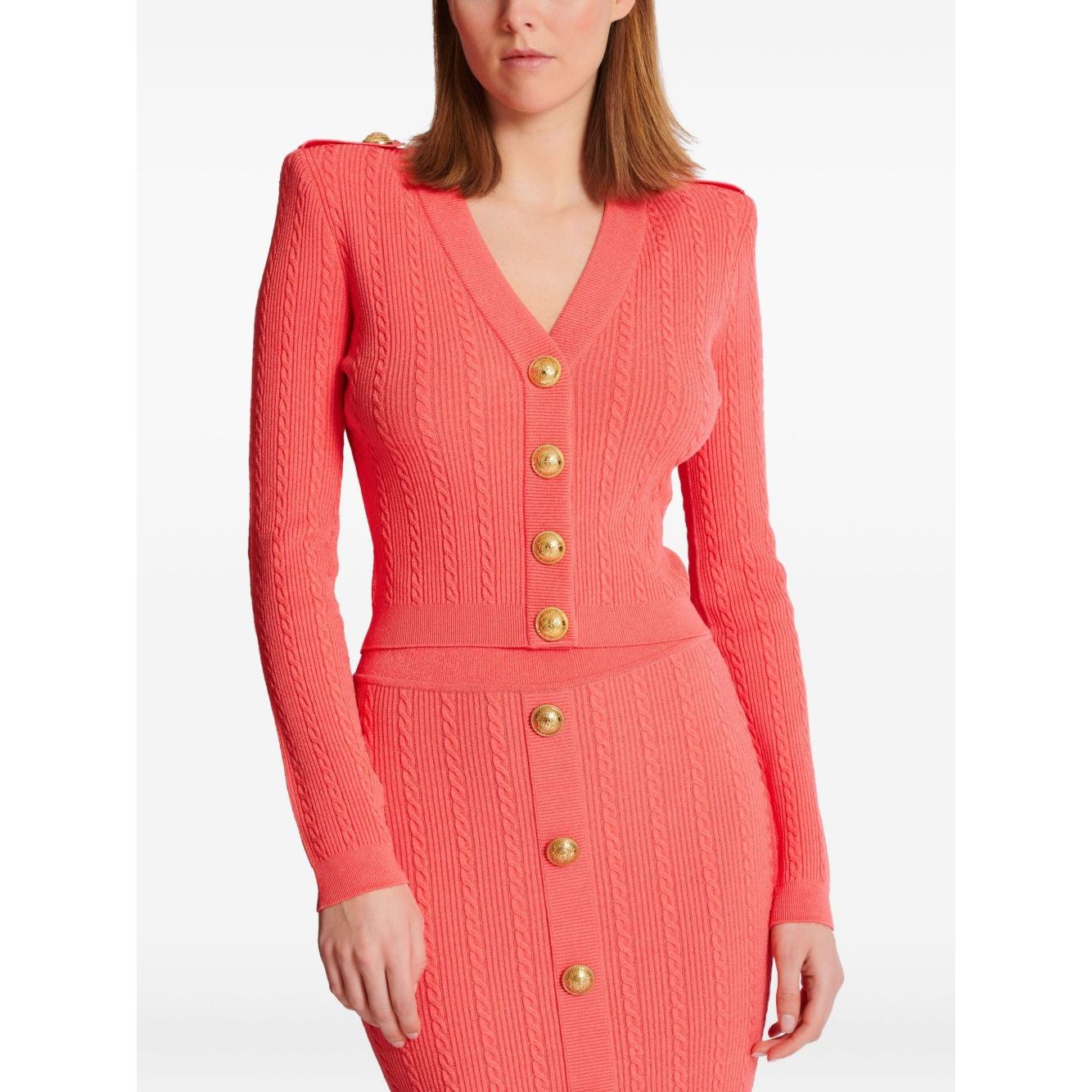 Balmain Long-sleeved twisted knit cardigan in coral pink with gold logo-embossed buttons and epaulettes, featuring a plunging V-neck.