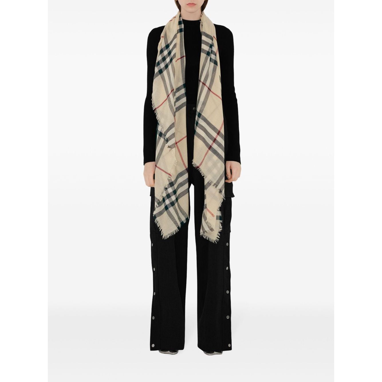 Model wearing Burberry Check wool scarf in beige with raw-cut edges and signature pattern, measuring 200x90 cm, displayed over black outfit.