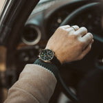 Gentleman's wrist wearing CASIO EDIFICE Mod. STANDARD CHRONOGRAPH GOLD - GREEN watch with leather strap in a car