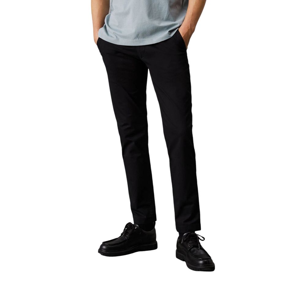 Calvin Klein Jeans Black Recycled Cotton Chino Pants, tapered fit, styled with black shoes and a light gray shirt.