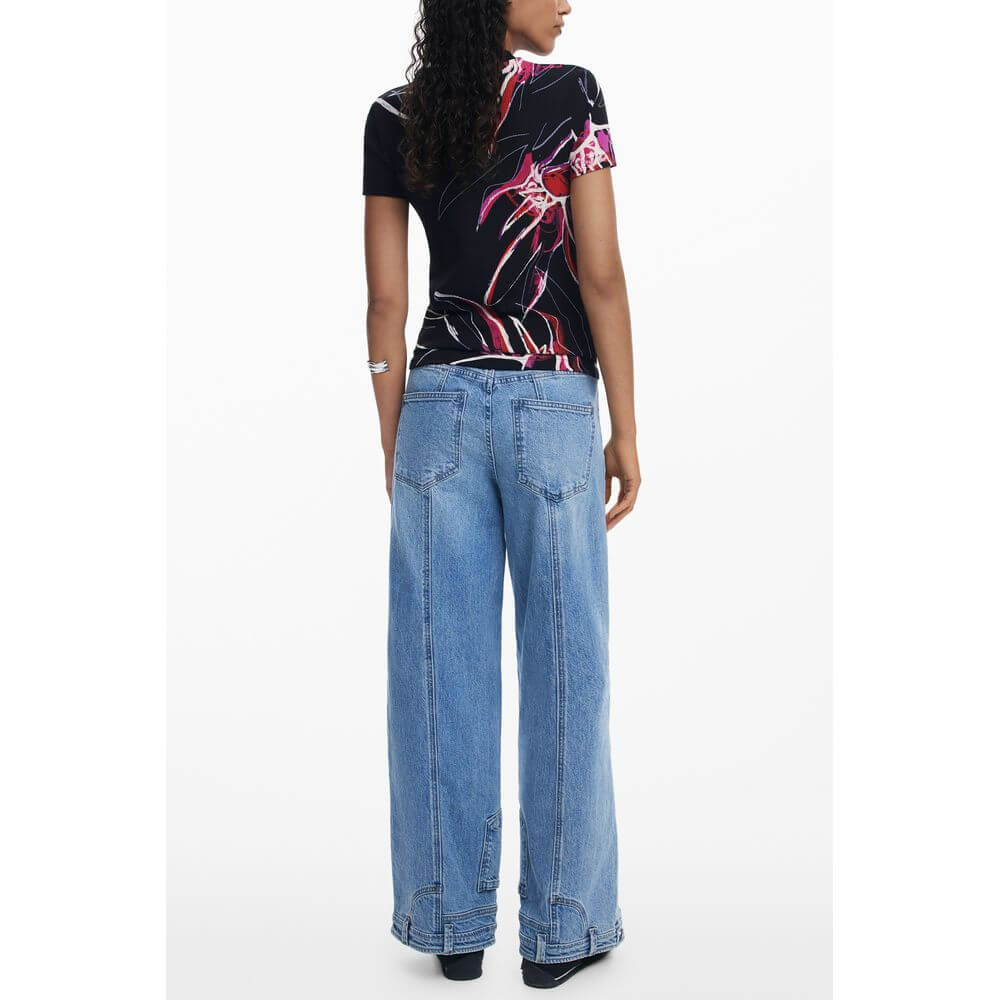 Back view of a woman wearing a Desigual Black Viscose Women Top with bold print, paired with wide-leg jeans.