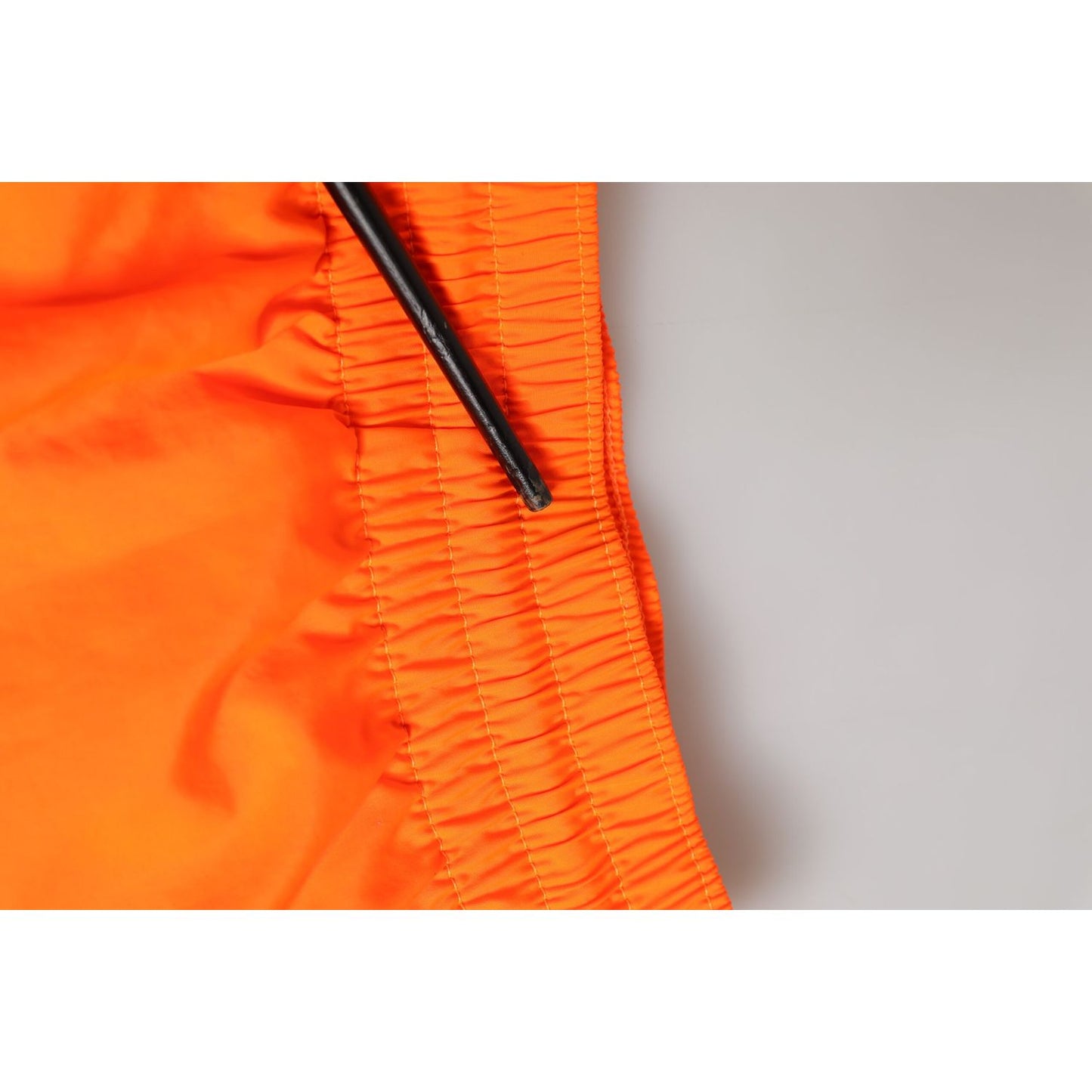 Close-up of Dolce & Gabbana Orange Polyester Beachwear Men Shorts Swimwear with elastic waistband and drawstring.