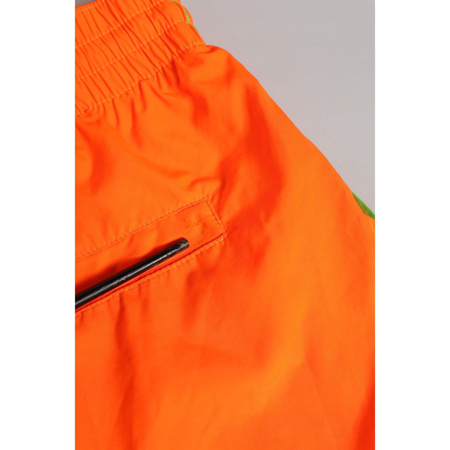 Close-up of Dolce & Gabbana Orange Polyester Beachwear Men Shorts Swimwear with elastic waist and zipper pocket.