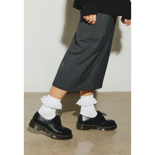Woman wearing Dr. Martens White Polyester Sock with black shoes and gray pants.