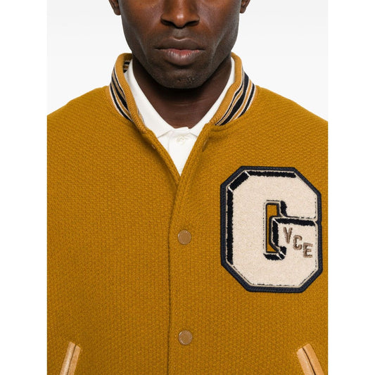Golden Goose Coats: mustard yellow bomber jacket with leather sleeves, varsity-style patches, ribbed trims, and welt pockets.