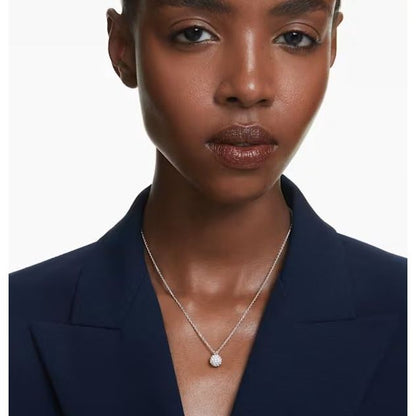 Woman wearing Swarovski necklace with a round pendant, showcasing elegant design and style.