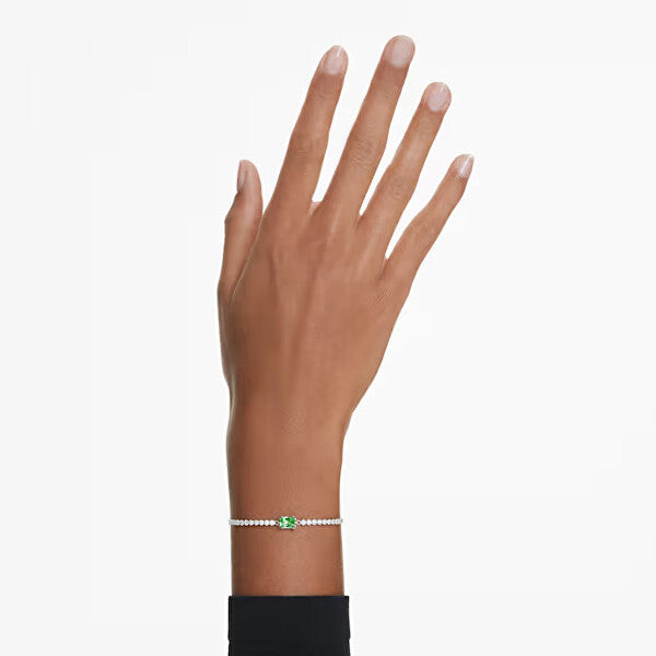 Elegant Swarovski bracelet with green gem on model's wrist, showcasing delicate design and sparkle.