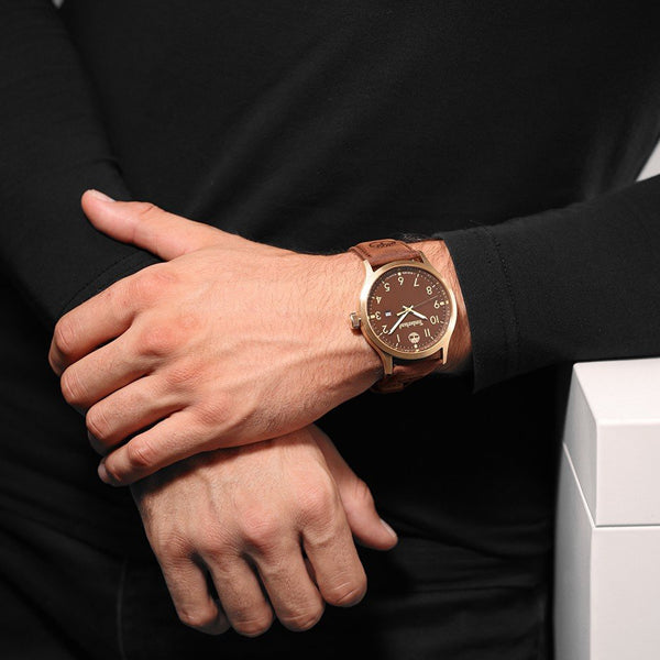 Gent's wrist wearing TIMBERLAND Mod. TRUMBULL, featuring gold stainless steel case and brown leather strap, 46mm, quartz movement.