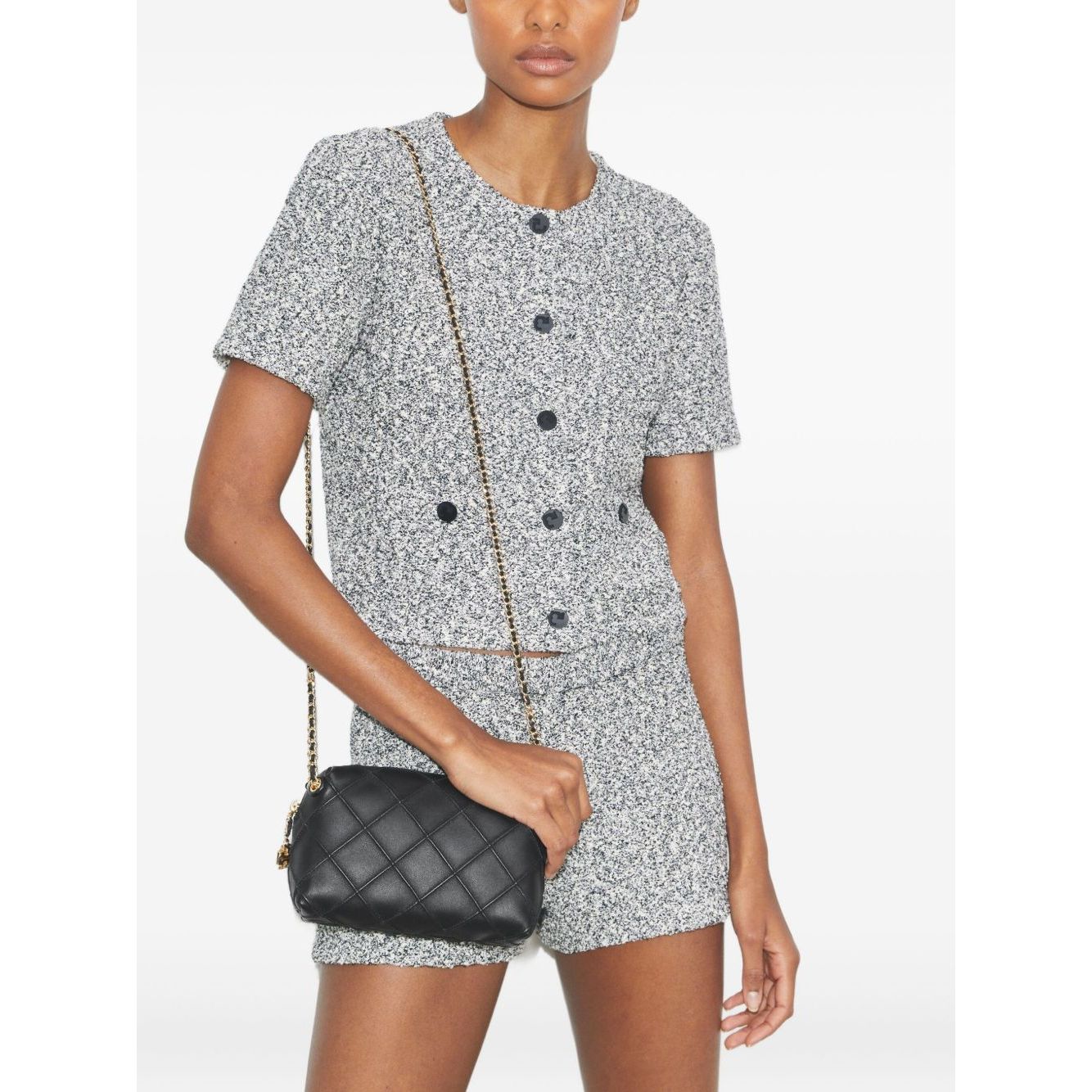 Model wearing Tory Burch small Fleming leather crossbody bag with black diamond quilted pattern and gold-tone chain strap