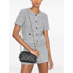Model wearing Tory Burch small Fleming leather crossbody bag with black diamond quilted pattern and gold-tone chain strap