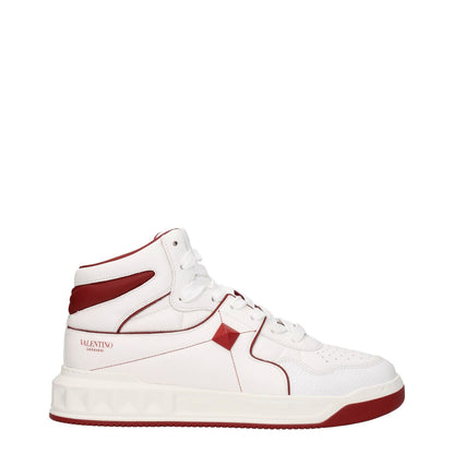 Valentino Garavani White Leather High Top Sneakers with red accents, featuring studs and logos, lace-up closure, and rubber sole.